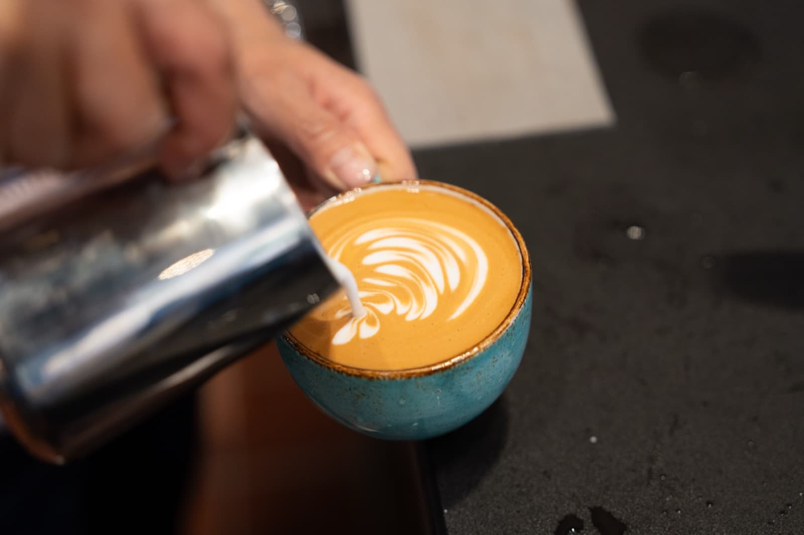 Barista pouring a latte at Plucky’s Cafe in Burlingame