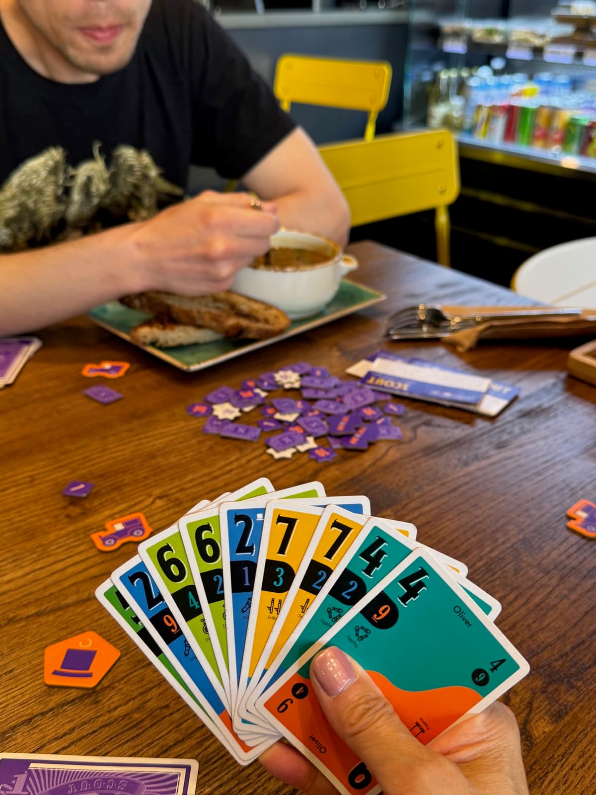 Players holding cards at a cafe table