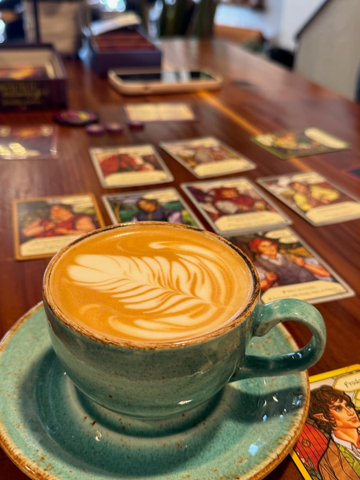 A latte beside a card game in progress
